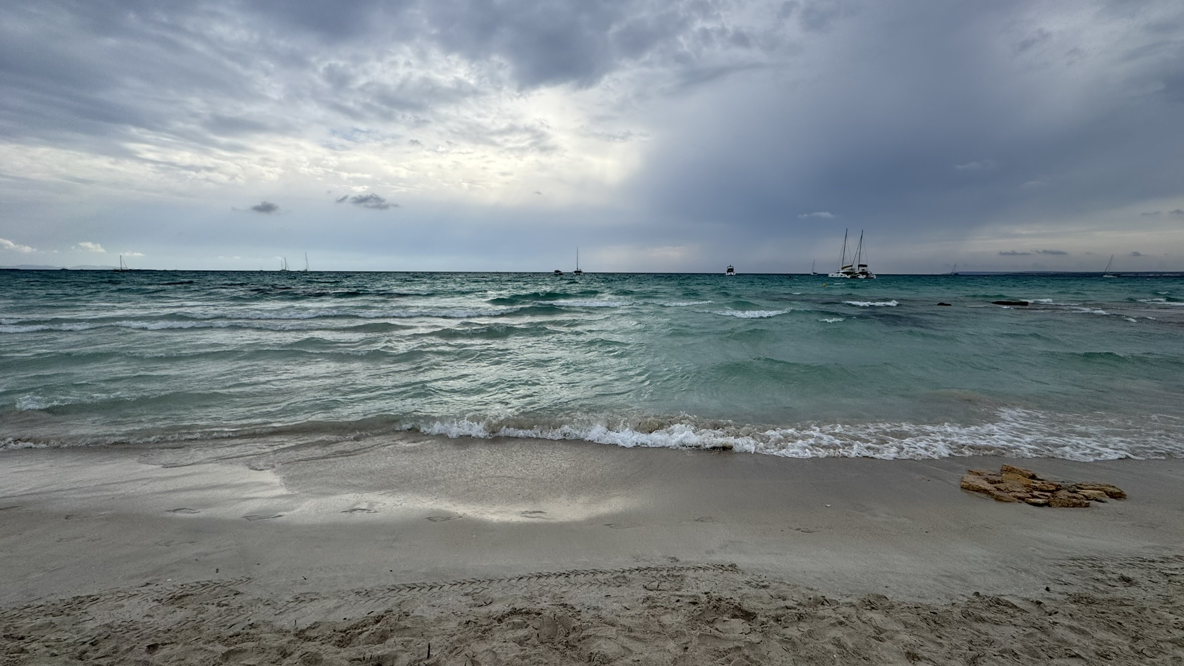 Cloudy sky over a turquoise sea and sandy shore